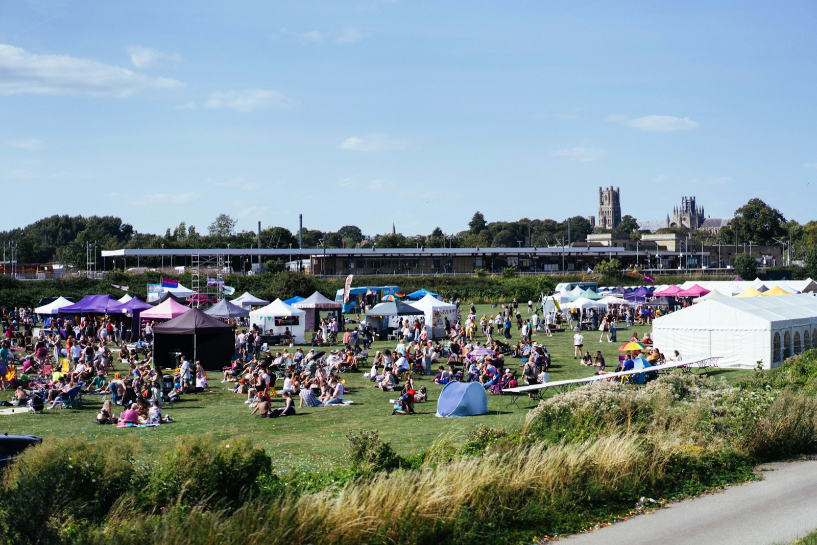 Outdoor festival on a lawn with many white and colored vendor tents.