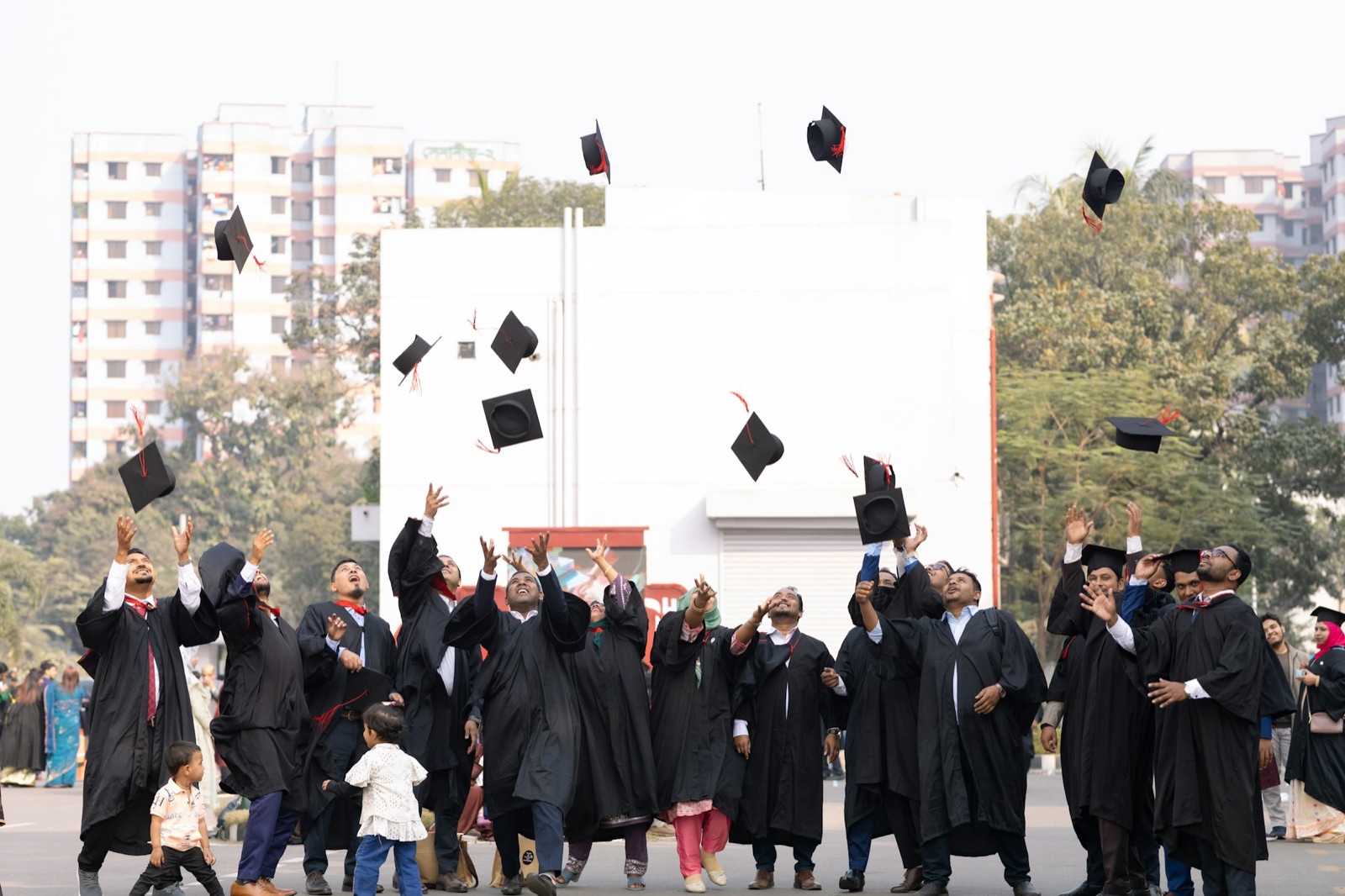 Graduates tossing black caps outdoors.